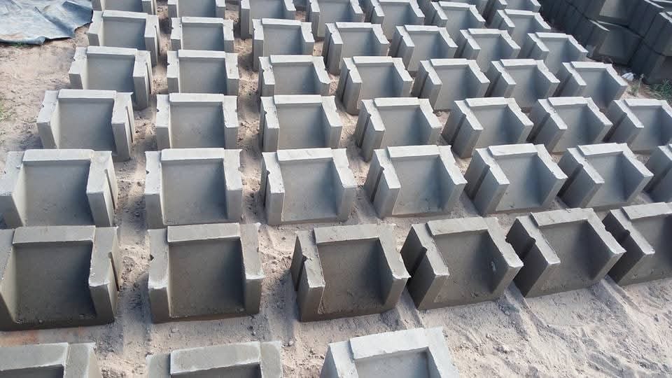 UCB hollow U-shaped concrete blocks stacked in rows at the Unique Concrete Builders yard in Kenya — hollow core masonry blocks for partition walls and boundary construction