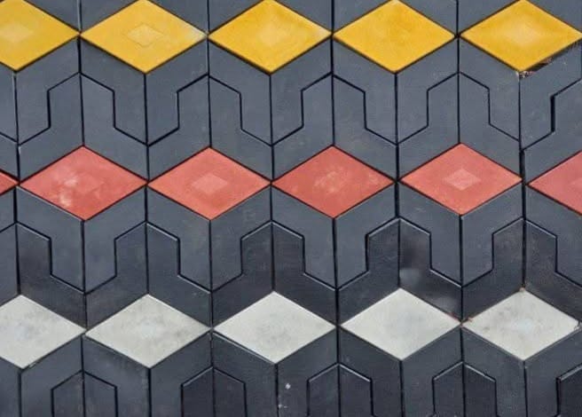 UCB Arrow Cabro Pavers installed — black interlocking pavers with yellow, red and white diamond-shaped inserts creating bold geometric rows by Unique Concrete Builders Kenya