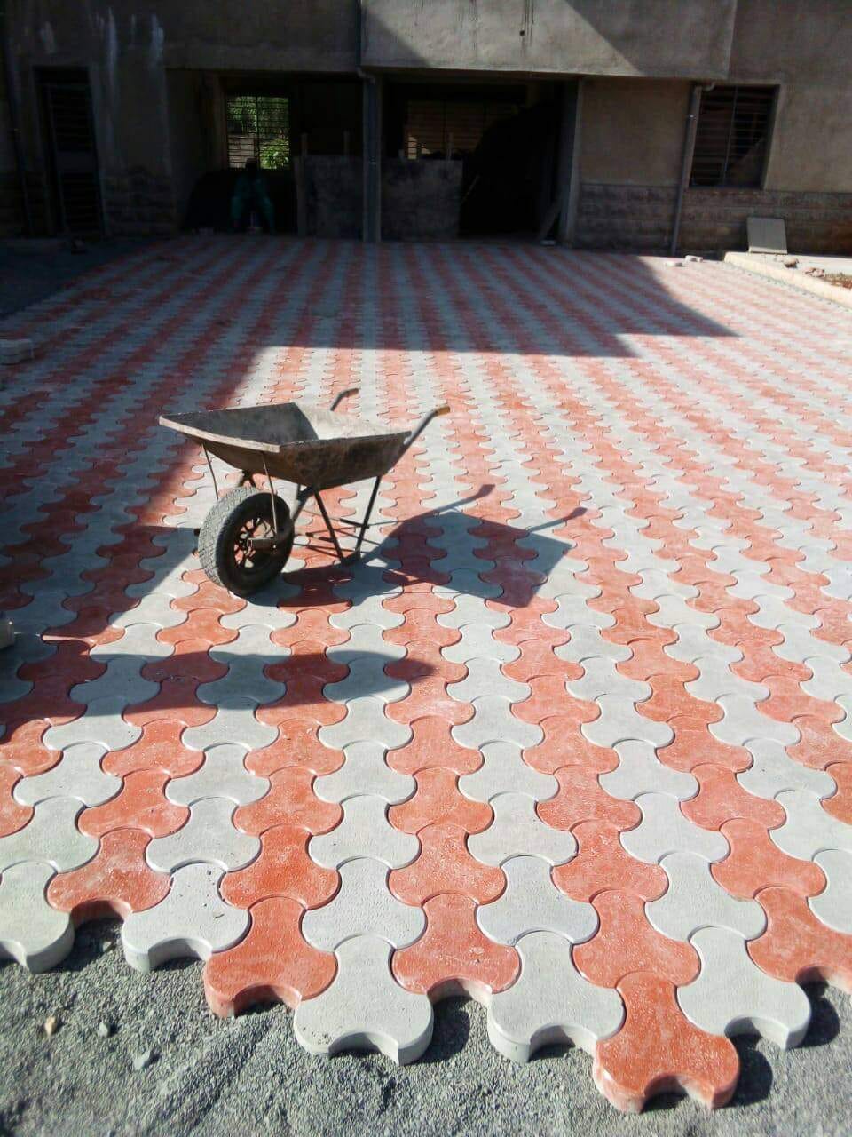 UCB Flower Paver installed on a compound in Kenya — red and grey curved 4-petal clover interlocking concrete pavers in a decorative pattern by Unique Concrete Builders